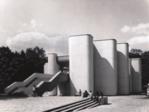 <p style="text-align: justify;">Santuokų rūmai yra įsikūrę sename parke, kur iki Antrojo pasaulinio karo buvo evangelikų liuteronų kapinės<a title="" href="#_ftn1">[1]</a>. Rūmų projektą sukūrė architektas Gediminas Baravykas 1968 – 1970 metais, tačiau statybos buvo baigtos tik 1974 metais. Rūmų konstruktorius Algimantas Katilius, baldų projektuotojas Eugenijus Gūzas, vitražų autorius dailininkas Konstantinas Šatrūnas<a title="" href="#_ftn2">[2]</a>. Pastato pirmasis aukštas buvo skirtas administracinėms reikmėms, o reprezentacinės patalpos suprojektuotos antrajame pastato aukšte. Patalpos suskirstytos linijinio centrinio komponavimo principu pagal palaipsniui didėjančią apeigų svarbą<a title="" href="#_ftn3">[3]</a>.</p>
<p style="text-align: justify;">Pastato pirmame aukšte buvo įkurdintas Vilniaus civilinės metrikacijos skyrius, jo archyvas, taip respublikinis civilinės metrikacijos archyvas, fotolabaratorija ir pagalbinės patalpos<a title="" href="#_ftn4">[4]</a>. Į sales sutuoktuvių ir vardinių apeigoms atlikti, kurios buvo suprojektuotos antrame pastato aukšte, vedė platūs laiptai tiesiai iš aikštės. Anot rūmus suprojektavusio architekto G. Baravyko, toks pasirinkimas padarytas atsižvelgiant į tai, jog „čia rinksis smalsuoliai, mėgstantys stebėti įeinančius ir išeinančius jaunuosius su palydomis, todėl jiems būriuotis taip pat rezervuota tam tikra erdvė“<a title="" href="#_ftn5">[5]</a>.</p>
<p style="text-align: justify;">Pastato įvadinėje dalyje išdėstytos abiems apeigoms naudoti bendros patalpos – vestibiulis, rūbinė, tualetai. Už jų, abipus iškilmingoms eisenoms skirto tako, sujungiančio įėjimo vestibiulį, svečių ir foto laukiamuosius, buvo numatytos santuokų ir varduvių patalpų grupės<a title="" href="#_ftn6">[6]</a>. Gana visapusiškai naujojo statinio patalpų išdėstymo funkcionalumą įvertino sovietinė spauda: „...Atvažiuoja jaunavedžiai su palyda. Išlipa prie plačių laiptų, mašinos pro jų apačią pasuka į parkingą. Jaunieji įeina į vidų. Rūbinė, veidrodžiai. Registracijos sektoriai. Labai jaukūs atskiri jaunųjų kambariai: čia galima susitvarkyti tualetą, čia dar yra progos paskutinį kartą pasvarstyti... Paskui ceremonmeisteris per didžiulį laukiamąjį veda jaunavedžius ir palydą į iškilmių salę. Numatyta vieta ir „nematomam“ fotografui , erdvus kambarys jaunavedžiams, palydai nusifotografuoti, pasirūpinta ir patalpa šampanui ar midui paruošti. Baigus ceremoniją, sumainius žiedus, ryškiai apšviestu taku jaunieji traukia prie išėjimo, o laukiamojoje salėje, jaunavedžių kambariuose jau ruošiasi apeigoms kitos poros“<a title="" href="#_ftn7">[7]</a>.</p>
<p style="text-align: justify;">Šis sovietinės architektūros statinys dėmesio sulaukė ir tuometinėje Vokietijos demokratinėje respublikoje leistame architektūrai skirtame žurnale „ Architektur der DDR“, kuriame buvo įvertintos „apvalios pastato ansamblio formos, suteikiančios jam šventiškumo charakterį“<a title="" href="#_ftn8">[8]</a>. Tuo tarpu sovietinėje spaudoje, šio architektūrinio objekto idėja buvo glaudžiai susieta ir su gamtine aplinka: „Aplinkos faktorius – senas parkas – iš dalies diktavo projekto autoriui architektui G. Baravykui architektūrinę-erdvinę pastato kompoziciją, kuri pasižymi švelniomis, aptakiomis formomis, dvelkia žmogiška šiluma. Visi rūmų vestibiuliai ir laukiamieji kambariai maksimaliai įstiklinti, kad interjeras susilietų su parko erdve, jaustųsi betarpiška gamtos ir architektūros vienovė“<a title="" href="#_ftn9">[9]</a>.</p>
<p style="text-align: justify;">Pastato architektūriniam įspūdžiui ir dermės su gamtine aplinka sustiprinimui nemažai dėmesio buvo skirta interjerui ir apeigas atlikusių tarnautojų išorei. Iškilmingumo įspūdžiui sustiprinti santuokų ir vardinių salės suprojektuotos aukštesnės, jų interjeras uždaresnis. Patalpų apdaila pasižymėjo medžiagų kontrastingumu – vertikaliai rievėtas tinkas, marmuro grindys, kabančios „travertino“ lubos. Iš aplinkos išsiskyrė tik atskiri ryškesnės spalvos elementai ir baldai, taip pat varduvių ir santuokų salių languose įkomponuotas LTSR herbas<a title="" href="#_ftn10">[10]</a>. Architekto E. Gūzo suprojektuotais baldais siekta organiškai papildyti pastato architektūrą ir interjerą. Rūmuose vyravo vyšninė spalva, kurią papildė gelsva ir samaninė. Prie interjero buvo pritaikyta ir civilines apeigas atlikusių tarnautojų apranga – sidabru siuvinėta uniforma<a title="" href="#_ftn11">[11]</a>. Beveik autentišką architektūrą ir interjerą išlaikiusiuose Vilniaus santuokų rūmuose iki šiol registruojamos civilinės santuokos.</p>
<p style="text-align: justify;"><em>Brigita Tranavičiūtė</em></p>
<div style="text-align: justify;"><br /><hr size="1" />
<div>
<p><a title="" href="#_ftnref1">[1]</a> Drėmaitė M., Petrulis V., Tutlytė J. Architektūra sovietinėje Lietuvoje. Vilnius: VDA leidykla, 2012,  </p>
</div>
<div>
<p><a title="" href="#_ftnref2">[2]</a> Lietuvos TSR istorijos ir kultūros paminklų sąvadas, t. 1, Vilnius, 1988, p. 309.</p>
</div>
<div>
<p><a title="" href="#_ftnref3">[3]</a> A. Čerbulėnas, J. Glemža, A. Jankevičienė ir kt. Vilniaus architektūra, Vilnius, 1985, p. 190.</p>
</div>
<div>
<p><a title="" href="#_ftnref4">[4]</a> E. Pranckūnas, Rūmai ant Tauro kalno. Literatūra ir menas, 1975 m. sausio 11 d., nr. 2.</p>
</div>
<div>
<p><a title="" href="#_ftnref5">[5]</a> G. Baravykas, Sutuoktuvių rūmai vilniečiams. Statyba ir architektūra, 1972, nr. 7, p. 11.</p>
</div>
<div>
<p><a title="" href="#_ftnref6">[6]</a> G. Baravykas, Sutuoktuvių rūmai vilniečiams. Statyba ir architektūra, 1972, nr. 7, p. 11.</p>
</div>
<div>
<p><a title="" href="#_ftnref7">[7]</a> E. Pranckūnas, Rūmai ant Tauro kalno. Literatūra ir menas, 1975 m. sausio 11 d., nr. 2.</p>
</div>
<div>
<p><a title="" href="#_ftnref8">[8]</a> D. K. Der Hochzeitspalast in Vilnius. Architektur der DDR, 1977, nr. 11,  p. 679.</p>
</div>
<div>
<p><a title="" href="#_ftnref9">[9]</a> E. Pranckūnas, Rūmai ant Tauro kalno. Literatūra ir menas, 1975 m. sausio 11 d., nr. 2.</p>
</div>
<div>
<p><a title="" href="#_ftnref10">[10]</a> A. Čerbulėnas, J. Glemža, A. Jankevičienė ir kt. Vilniaus architektūra, Vilnius, 1985, p. 191.</p>
</div>
<div>
<p><a title="" href="#_ftnref11">[11]</a> E. Pranckūnas, Rūmai ant Tauro kalno. Literatūra ir menas, 1975 m. sausio 11 d., nr. 2.</p>
</div>
</div>